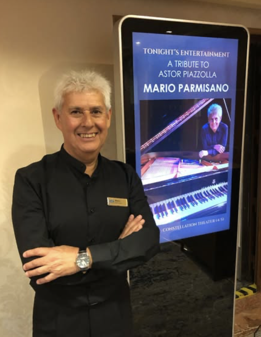 Mario Parmisano beside the announcement for his tribute to Astor Piazzolla aboard Regent Seven Seas