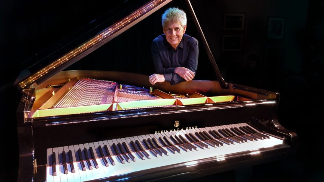 Mario Parmisano beside a Steinway grand piano